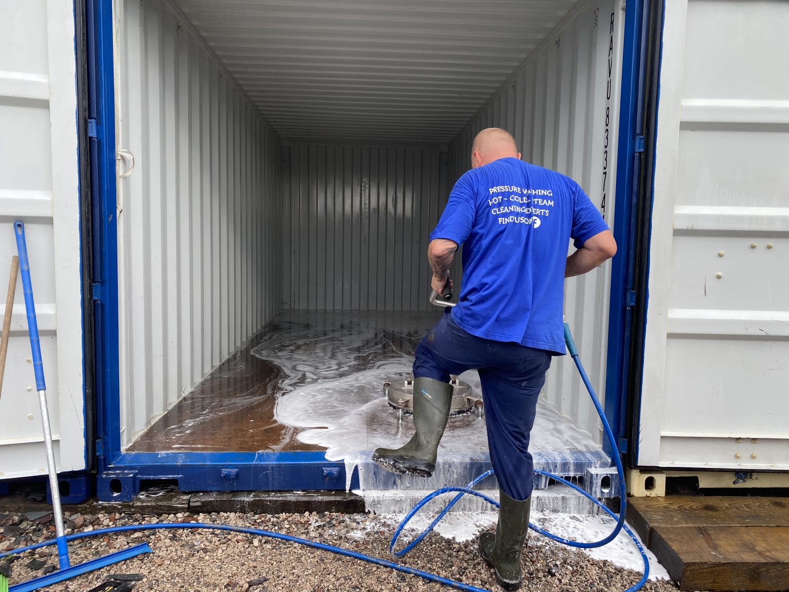 Man pressure washing interior of a shipping container